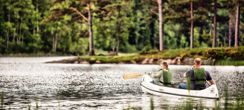 En familj som paddlar kanot i Naturbyn