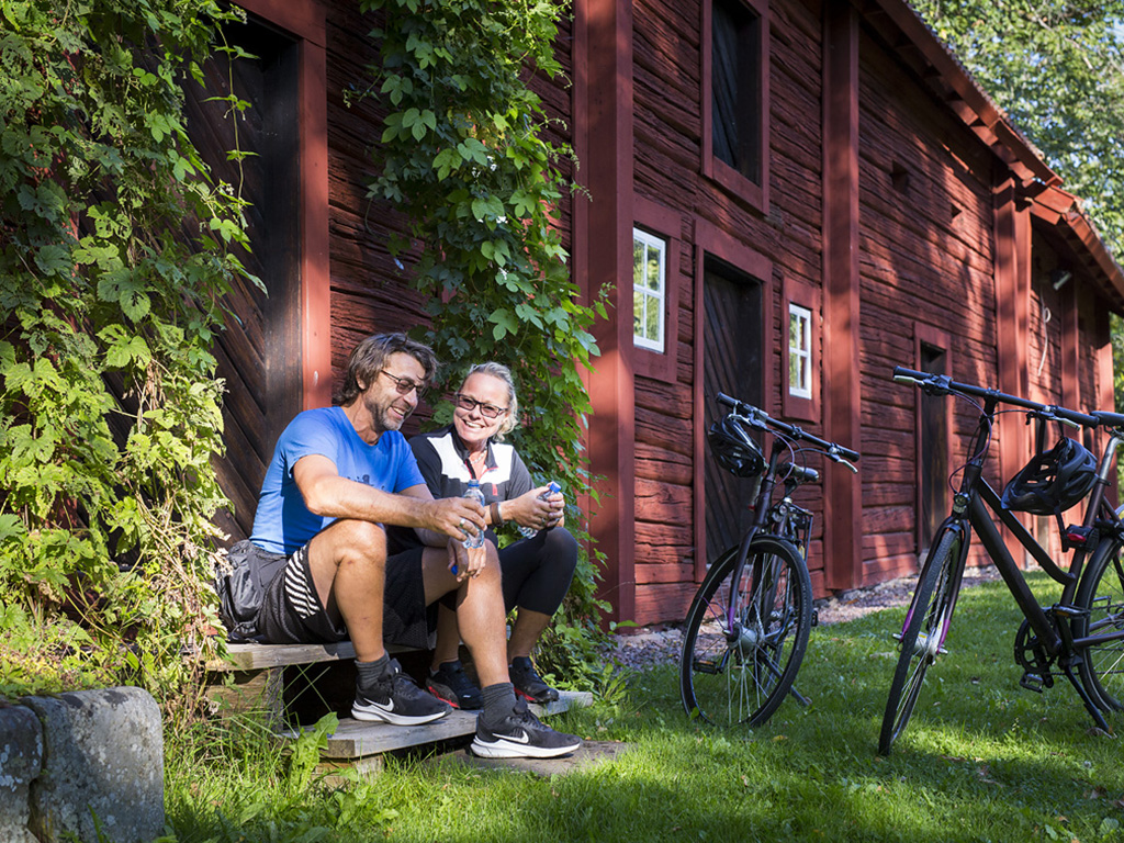 Cyclists take a break by a red timber building Photo: Roger Borgelid